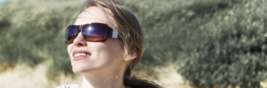 woman's face staring into sun on a beach