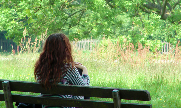 woman sitting on bench overlooking meadow