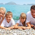 young healthy family lying on ocean beach facing viewer